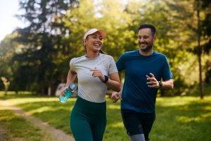 Happy athletic couple having fun while running together in nature.