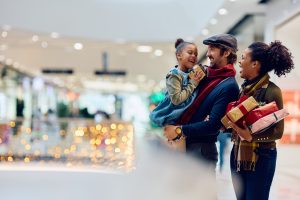 Happy family having fun while buying Christmas presents at shopping mall. Copy space.